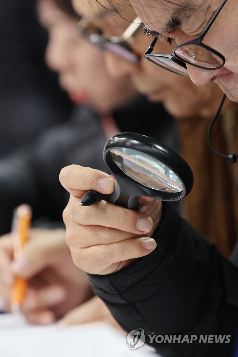 돋보기로 취업정보 살펴보는 구직자