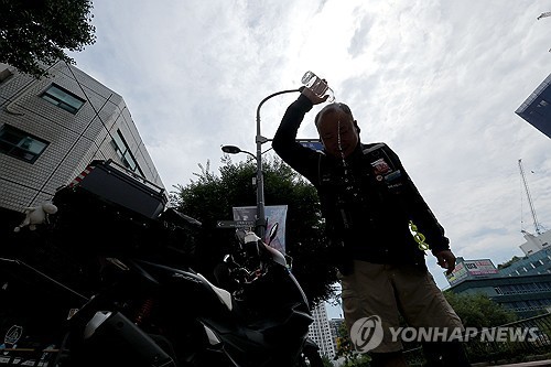 서울 시내에서 한 배달 노동자가 물을 뿌리며 더위를 식히는 모습